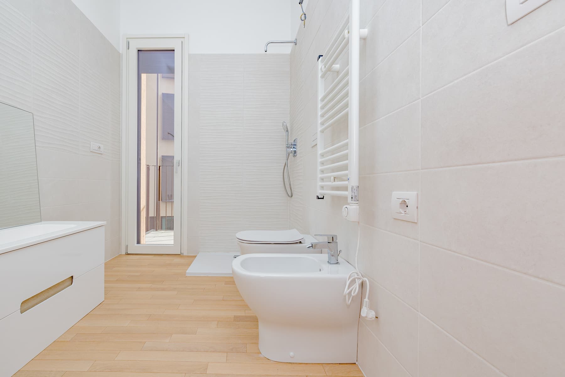 Bianco e parquet chiaro: Rivestimento chiaro a tutta altezza, mobile sospeso bianco e pavimento effetto legno chiaro.